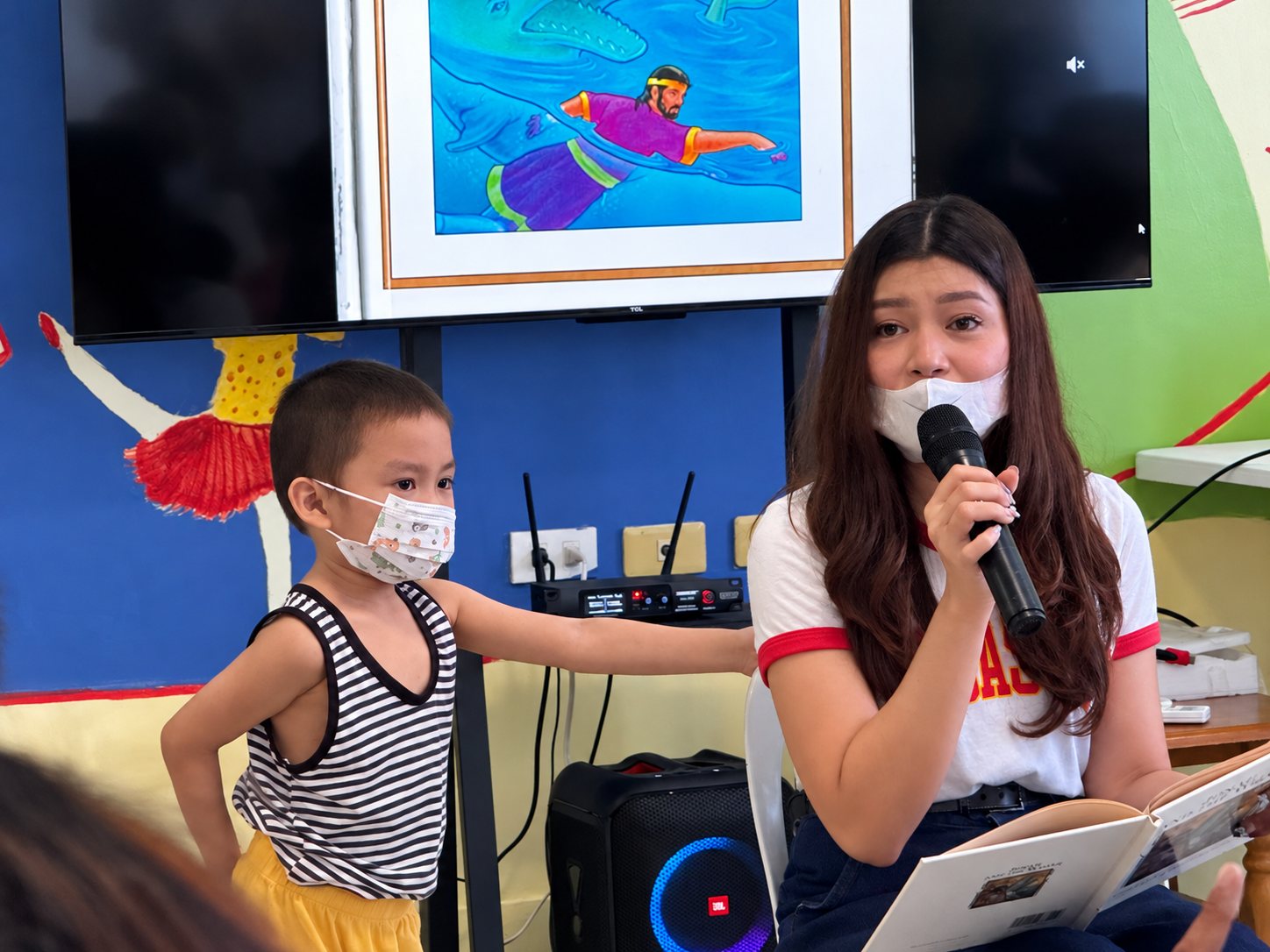 An Aereach volunteer on the microphone with one of the children.
