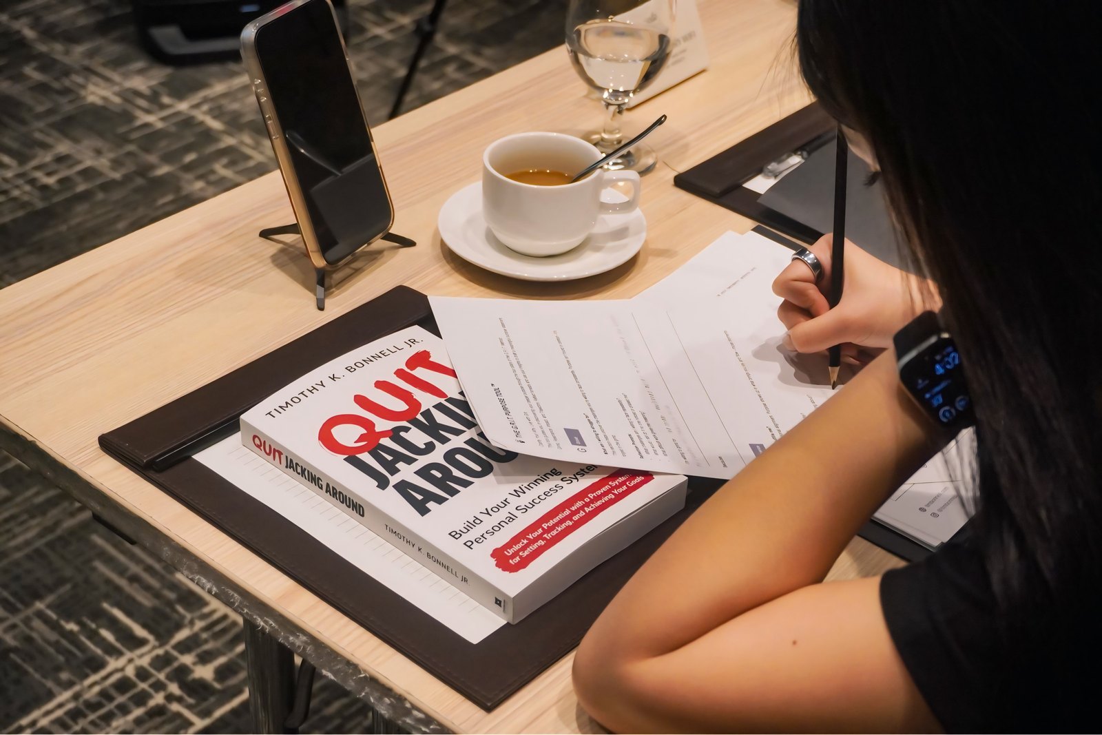 A participant writing in her workbook beside a copy of Quit Jacking Around.